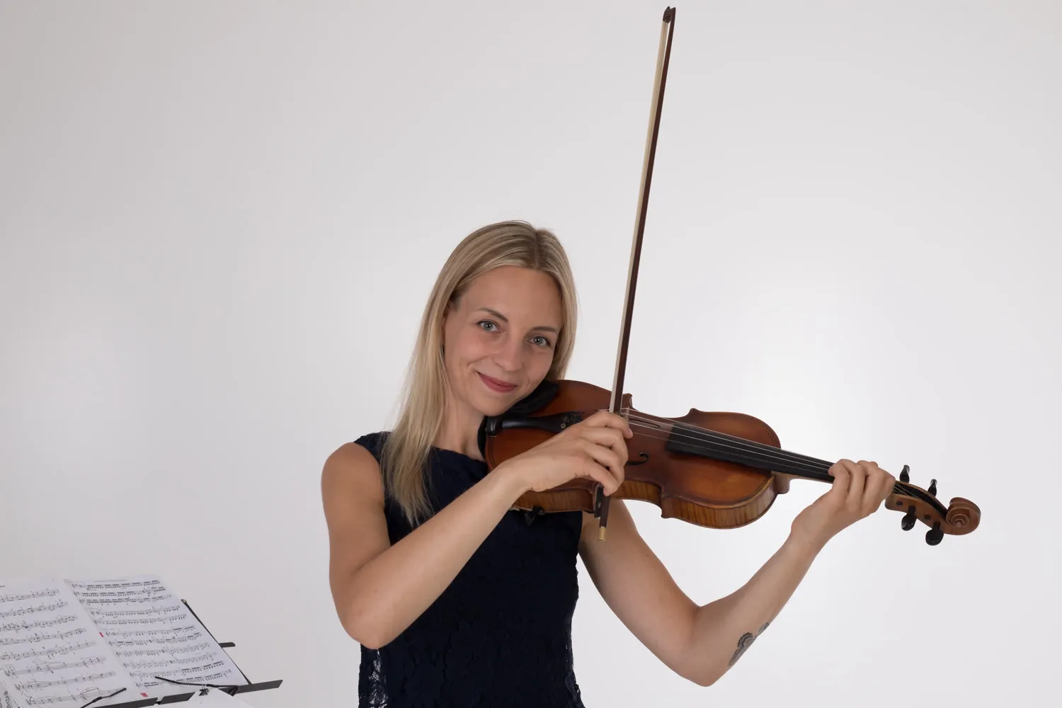 Marta playing violin with a music stand beside her